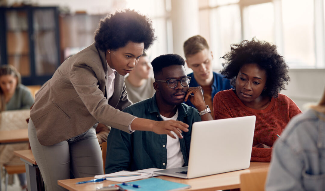 African American professor and her students using laptop during lecture in the classroom.
